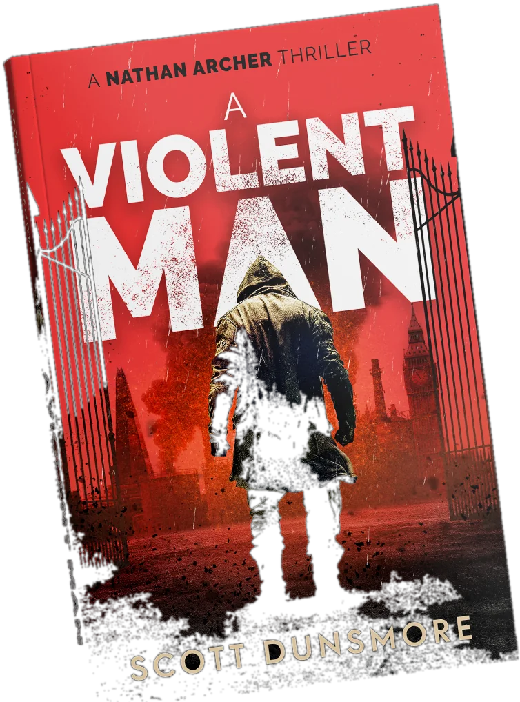 The paperback of A Violent Man by Scott Dunsmore, held at an angle: a hooded figure walks away through black iron gates under a red sky, with a city skyline behind him.